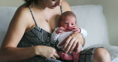 Mom holding newborn baby, first week of life, fragile