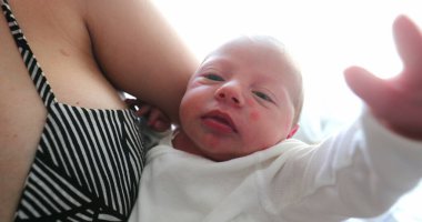 Mother holding newborn baby infant first days of life