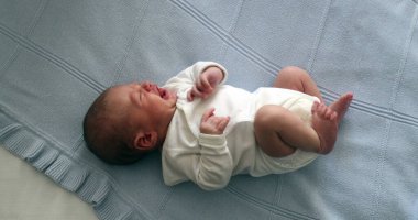 Newborn baby infant crying in bed