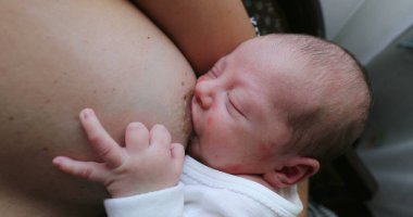 Newborn baby asleep while holding on mother breast