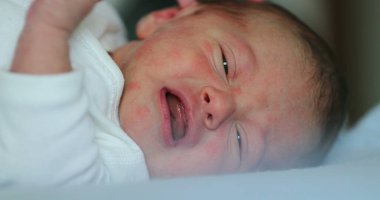 Newborn baby infant crying during first week of life, close-up of baby face
