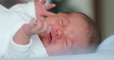 Newborn baby lying in beed looking to camera, first week of life