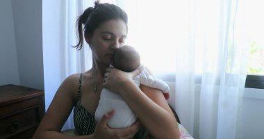 Mother holding newborn baby by window