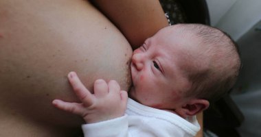 Newborn baby asleep while holding on mother breast