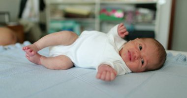 Newborn baby infant laid in bed stretching body