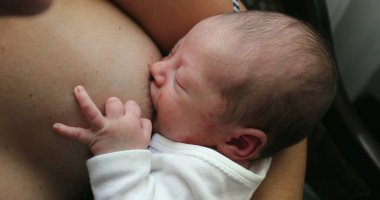 Newborn baby asleep while holding on mother breast, mother breastfeeding