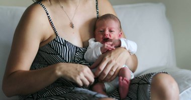 Mom holding newborn baby, first week of life, fragile
