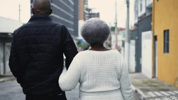非洲裔美国人的后背白发苍苍的母亲走在城市 80多岁的老太太抱着照顾者的手在外面细雨中 — 图库视频影像