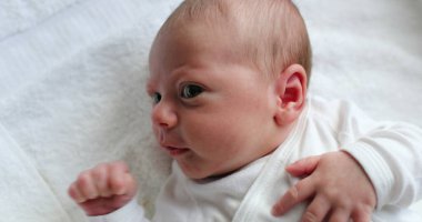 Closeup of newborn baby awake infant care during first days of life looking up