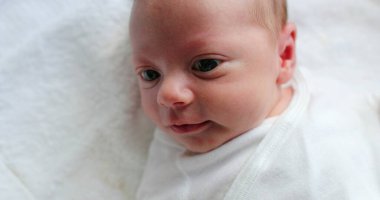 Closeup of newborn baby awake infant care during first days of life looking up