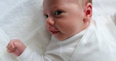Closeup of newborn baby awake infant care during first days of life looking up