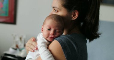 Mother holding newborn baby in her arms first days of life