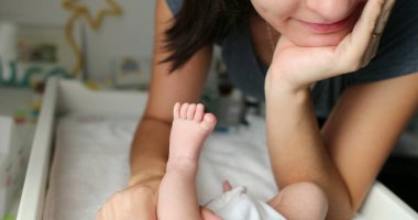 Mom holding and kissing newborn baby feet