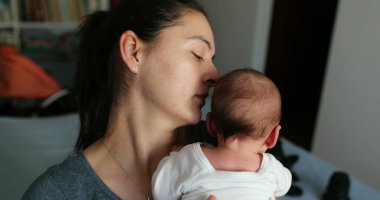 Mother tapping newborn baby back to help with hiccups