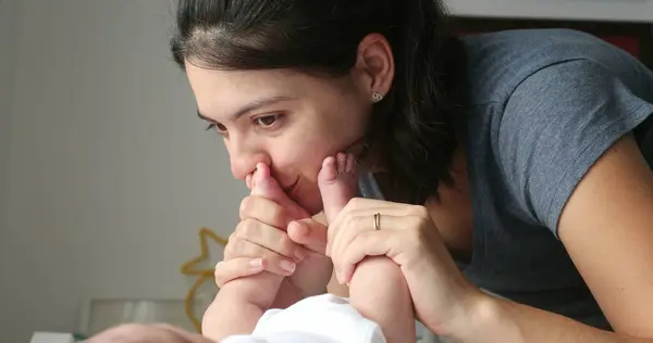 Mother kissing newborn baby feet and foot showing love affection and baby care