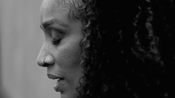 絶望的なアフリカ系アメリカ人女性は 劇的なモノクロマティック 黒と白で捉えられた都市環境の静かな絶望の中で目を閉じます 絶望的な人のクローズアッププロファイルの顔 — ストック動画