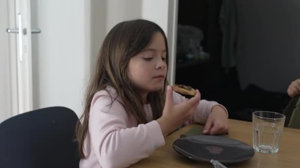 食事中に食べる小さな女の子が カメラの外で家族と交流しています チャイルドスナッキングエスファ — ストック動画