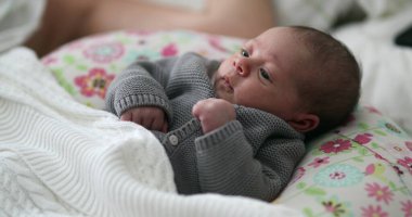 Cute adorable newborn baby infant awake in bed