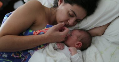 Mother lying in bed with newborn baby infant son