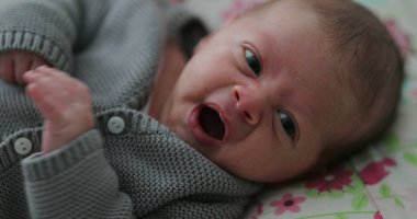 Newborn baby infant first month of old looking to camera yawning sleepy and crying