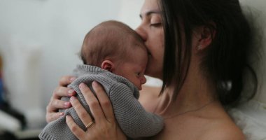 Candid mother holding newborn baby in bed showing love care and affection