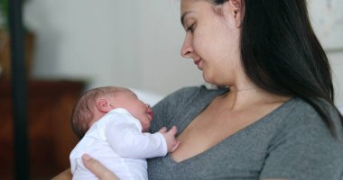 Mother holding newborn baby during first month of life casual and candid real life