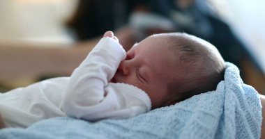 Infant newborn baby face close-up waking up from sleep