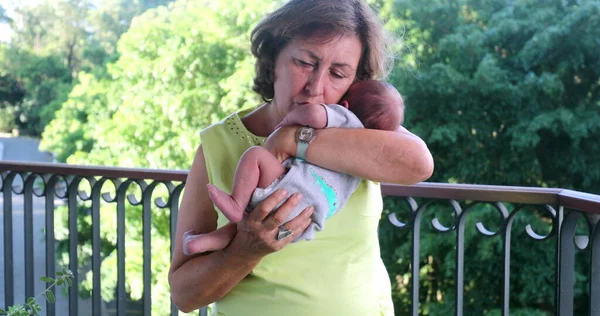 Grand-mother holding newborn grand-son baby infant showing love care and affection