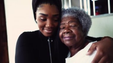 Afrikalı Amerikalı torun, 80 'lerin yaşlı büyükannesine sarılıyor. Nesiller arası aile üyelerine destek ve yardım ediyor. Yaşlılıkta aile birliği ve sevgi