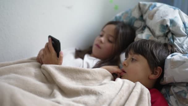Kinderen Liggen Bed Kijken Naar Mobiele Telefoon Apparaat Zus Delen — Stockvideo