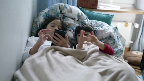 Дети Экраном Мобильного Телефона Кровати Простынями Младшие Брат Сестра Использованием — стоковое видео