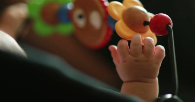 Baby hand playing with toy inside crib
