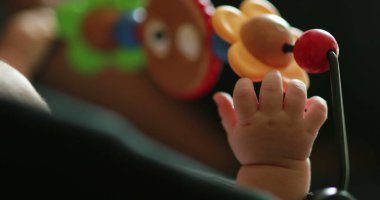 Baby hand playing with toy inside crib