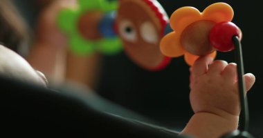 Baby hands playing with toy inside chair crib