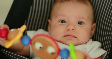 Baby newborn in chair seated with spinning toy in the foreground