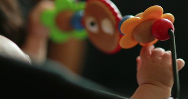 Baby hands playing with toy inside chair crib