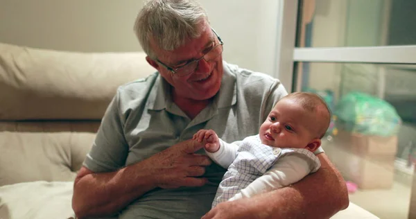 Grand-father holding grand-son baby infant in arms casual authentic family moment