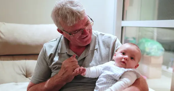 Grand-father holding grand-son baby infant in arms casual authentic family moment