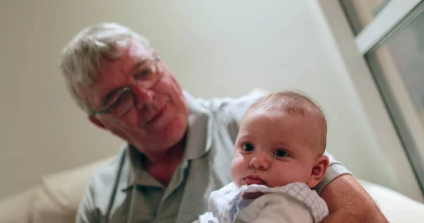 Candid grand-father holding newborn baby infant casual