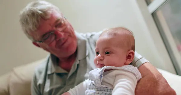 Candid grand-father holding newborn baby infant casual
