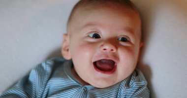 Joyful happy newborn baby smiling and laughing face expression