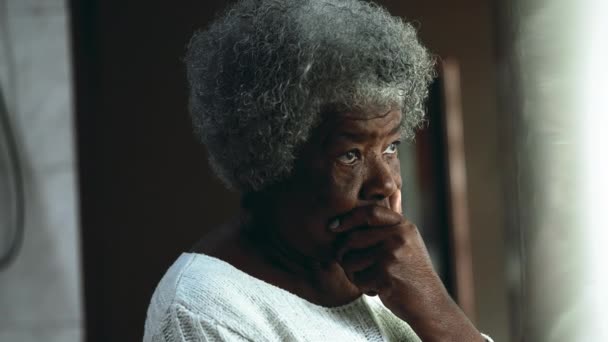 忧心忡忡的非洲裔美国老年妇女陷入沉思 站在窗前凝视着外面 沉思着沉思着 沉思着老年的描写 — 图库视频影像