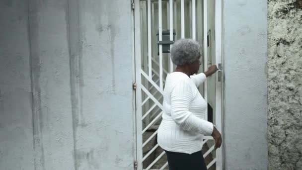 上了年纪的南美黑人妇女从人行道上回到家 关上大门回到家门前 80多岁的非洲裔老人 — 图库视频影像