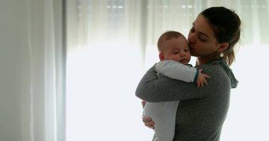 Real life authentic mom kissing and consoling crying infant baby