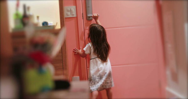 Small cute girl holding door knob