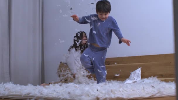 Carefree Siblings Playing Feathers Bouncing Bed Pillow Battle Aftermath Joyful — Stock Video