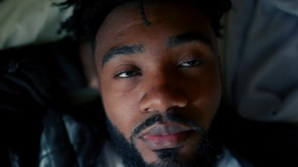 ベッドに横たわっている間 深い思考の若者 セリーンに反射する20代男性の閉じたアップ アフリカ系南アメリカ人の平和的な考え方 — ストック動画