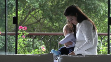 Anne oğlunu pencereye bakan pencerenin yanında tutuyor.