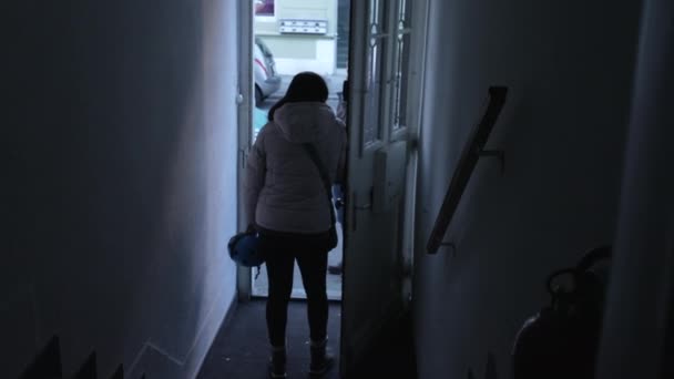 ムーディービルの入り口のドアの前で立っている女性の背中 住居を離れる準備ができている通りの誰かとチャット 青いトーン — ストック動画
