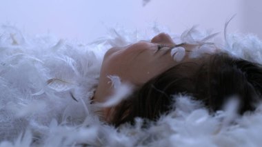 Tüyler çocuk yüzüne düşüyor. Huzurlu ve huzurlu bir anda yatağa uzanıyor. 1000 fps yavaş çekimde çekiliyor.